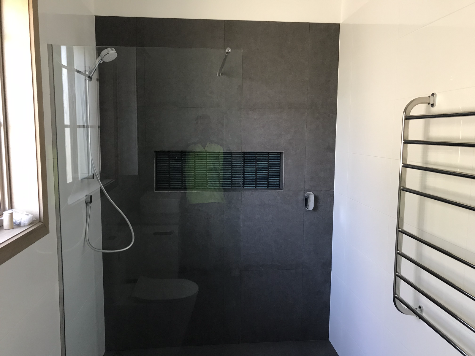 Modern bathroom with walk-in shower, glass enclosure, dark gray tiles, niche, towel rail, contemporary design